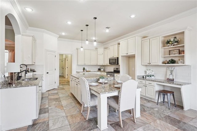 kitchen with sink, light stone countertops, appliances with stainless steel finishes, a kitchen island, and a kitchen bar