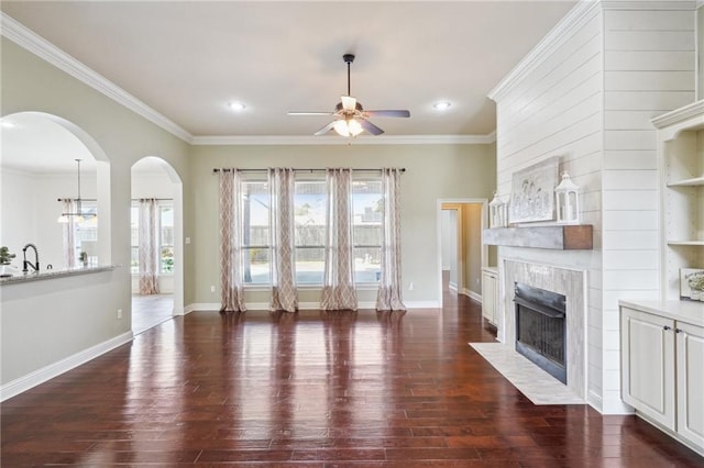 unfurnished living room with ceiling fan, dark hardwood / wood-style floors, crown molding, and a tile fireplace