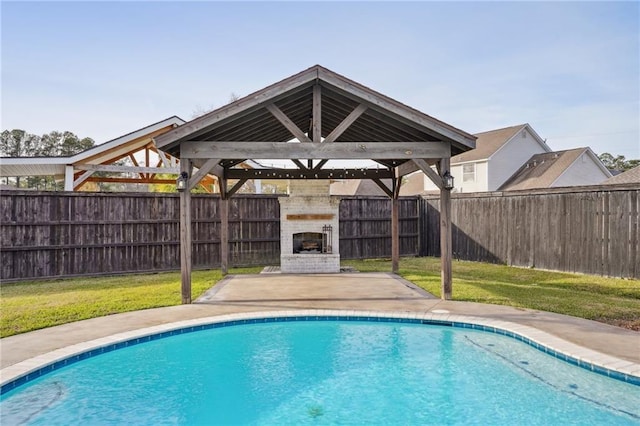 view of pool with a large fireplace and a yard