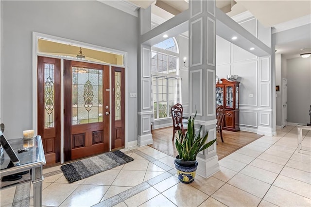 tiled foyer featuring a towering ceiling and ornamental molding