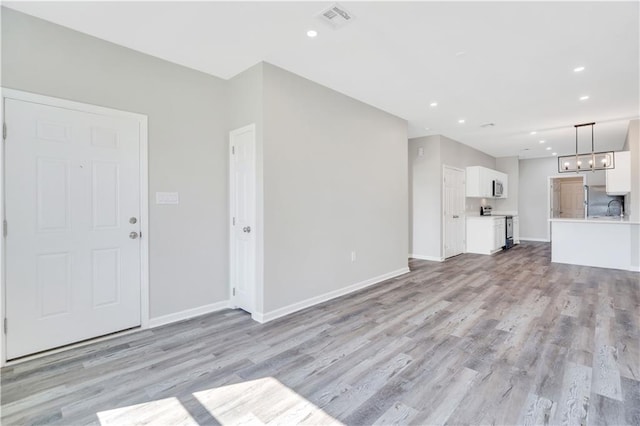 unfurnished living room with light hardwood / wood-style flooring and sink