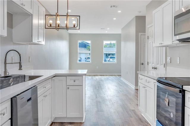 kitchen featuring sink, stainless steel appliances, a notable chandelier, decorative light fixtures, and white cabinets