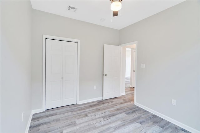 unfurnished bedroom with ceiling fan, light hardwood / wood-style flooring, and a closet