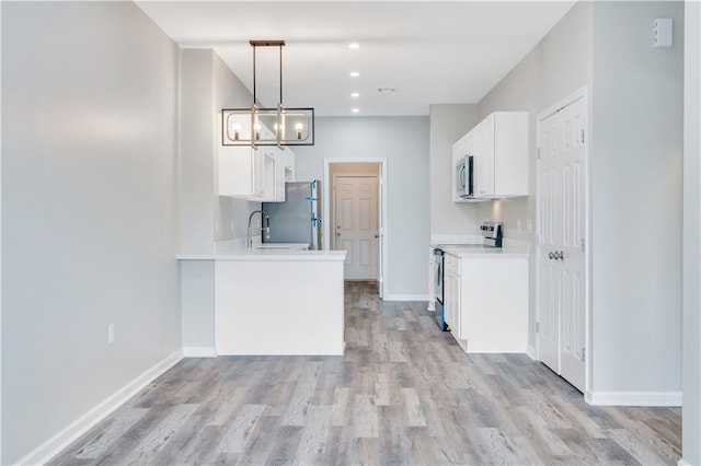 kitchen featuring hanging light fixtures, stainless steel appliances, kitchen peninsula, white cabinets, and light wood-type flooring