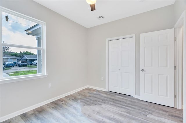 unfurnished bedroom with ceiling fan, light wood-type flooring, and a closet