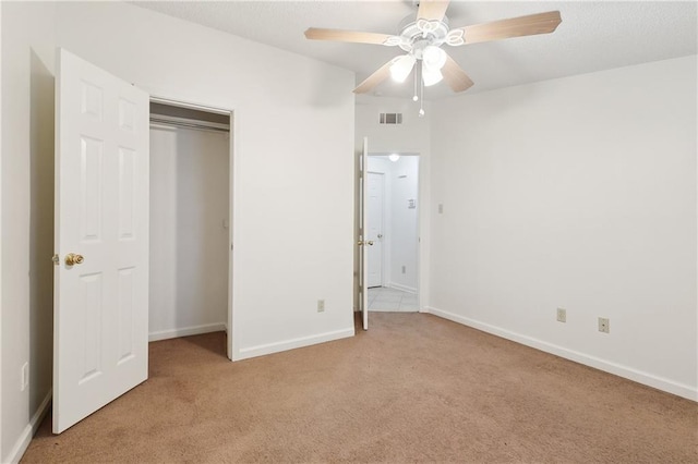 unfurnished bedroom featuring ceiling fan, a closet, and light colored carpet