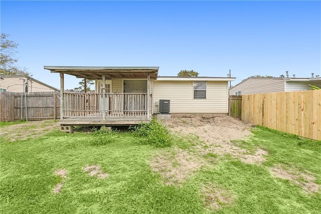 back of property with a deck, central AC unit, and a lawn