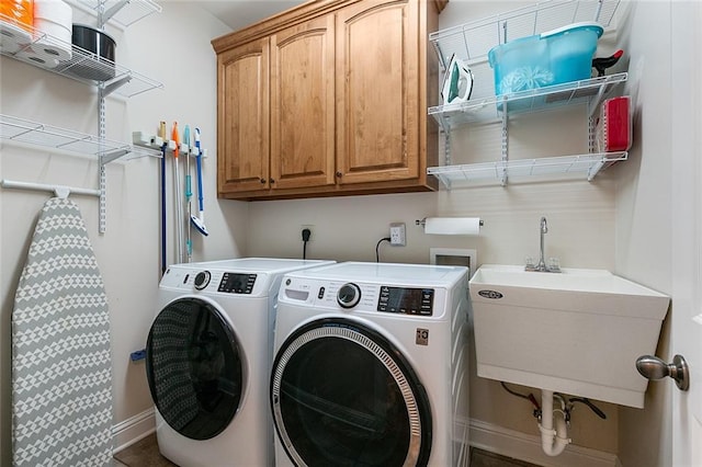 clothes washing area featuring cabinets, washing machine and dryer, and sink