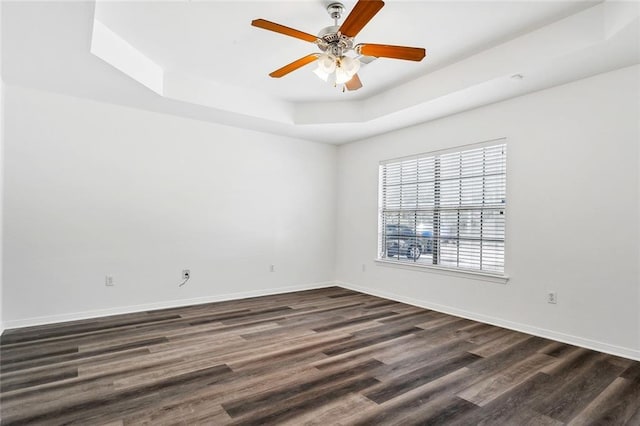 spare room featuring dark hardwood / wood-style floors, a raised ceiling, and ceiling fan