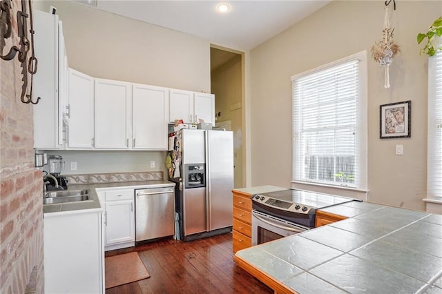 kitchen featuring tile countertops, sink, dark hardwood / wood-style flooring, white cabinetry, and stainless steel appliances