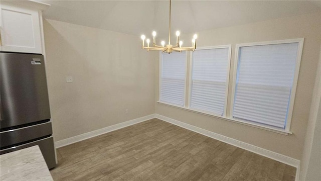 unfurnished dining area with light hardwood / wood-style flooring and an inviting chandelier