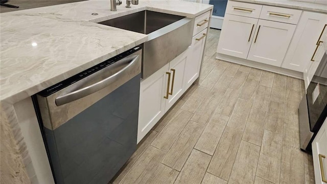 kitchen with white cabinets, dishwasher, light stone counters, and sink