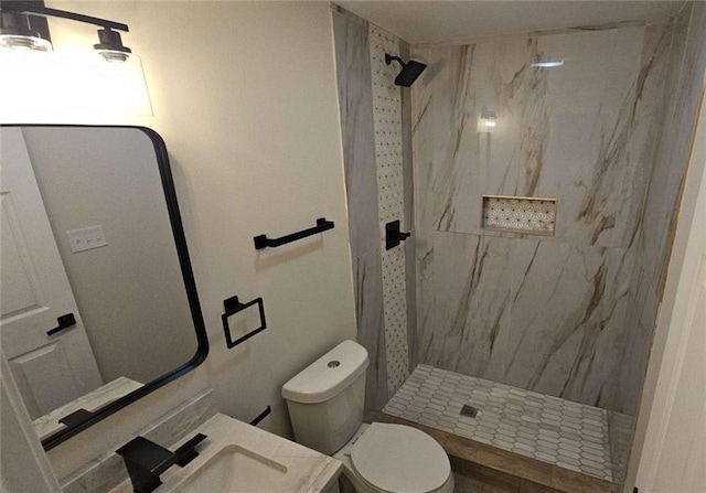 bathroom featuring a tile shower, vanity, and toilet