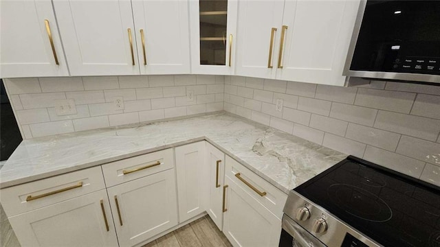 kitchen featuring white cabinets, light stone countertops, appliances with stainless steel finishes, and tasteful backsplash