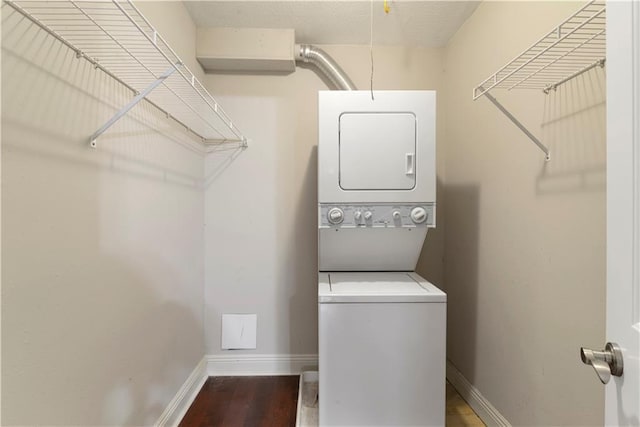 laundry area with dark hardwood / wood-style flooring and stacked washer and dryer