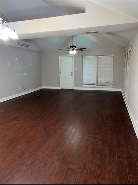 spare room with ceiling fan with notable chandelier, dark hardwood / wood-style floors, and lofted ceiling