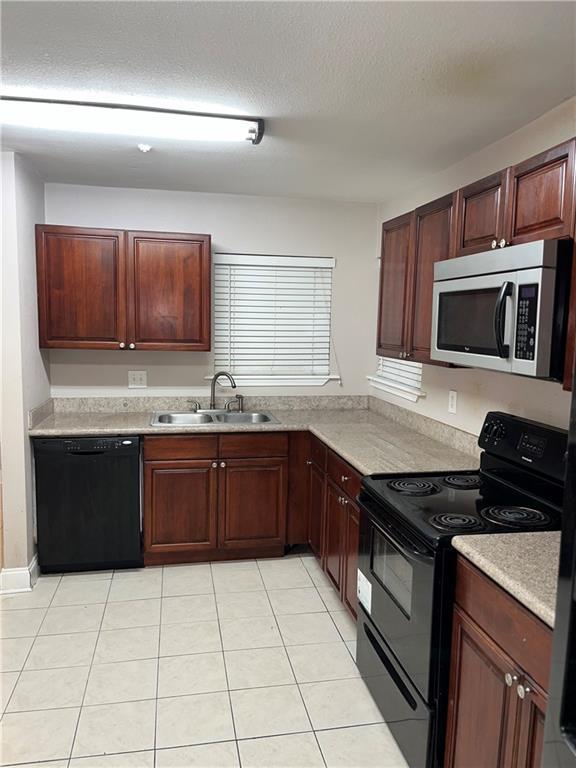 kitchen featuring light tile patterned floors, sink, a textured ceiling, and black appliances