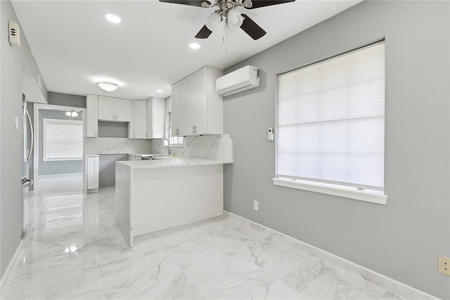 kitchen featuring sink, an AC wall unit, kitchen peninsula, decorative backsplash, and white cabinets