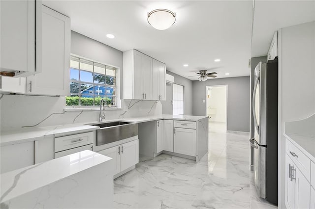 kitchen with sink, white cabinets, stainless steel refrigerator, and kitchen peninsula