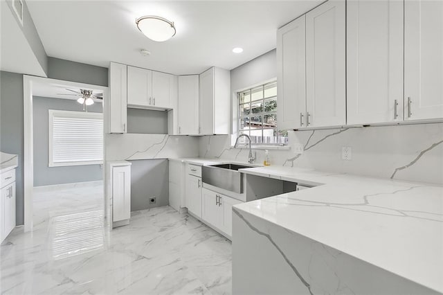 kitchen featuring light stone counters and white cabinetry