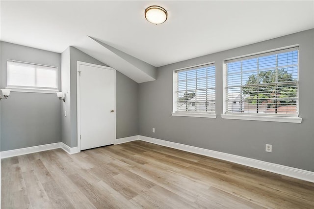 additional living space with vaulted ceiling and light wood-type flooring