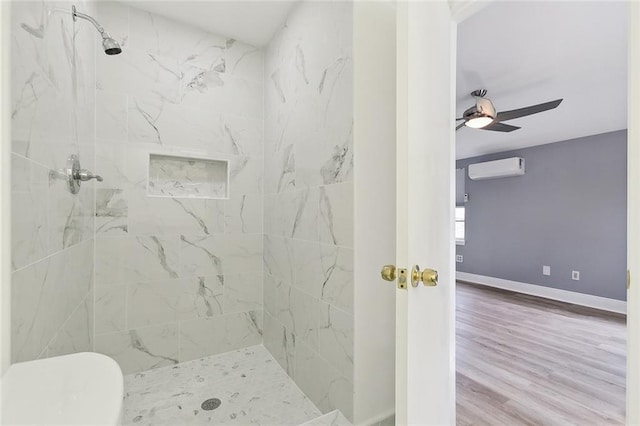 bathroom with a tile shower, ceiling fan, wood-type flooring, and a wall mounted AC