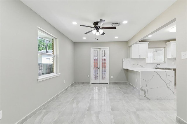 kitchen with white cabinetry, light stone countertops, ceiling fan, and french doors