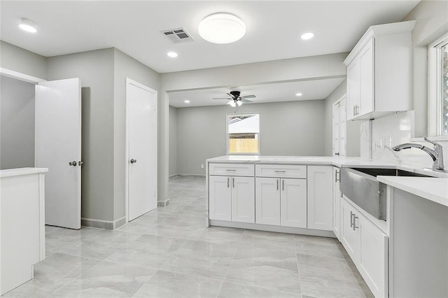 kitchen featuring sink, white cabinetry, tasteful backsplash, kitchen peninsula, and ceiling fan