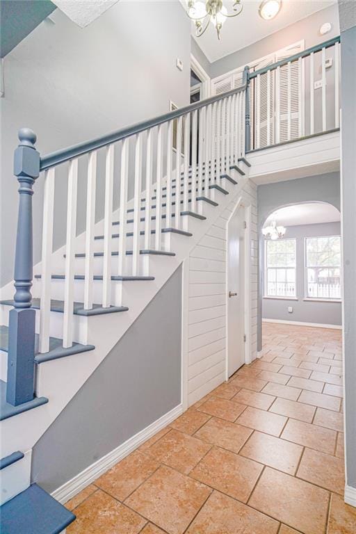 stairs featuring tile patterned flooring, a high ceiling, and a notable chandelier