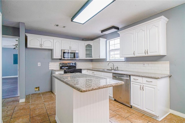 kitchen with white cabinetry, sink, ceiling fan, stainless steel appliances, and a kitchen island