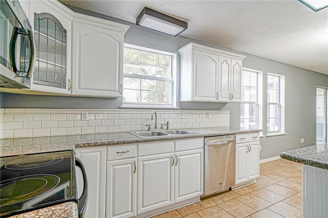 kitchen featuring appliances with stainless steel finishes, tasteful backsplash, sink, white cabinetry, and light tile patterned flooring