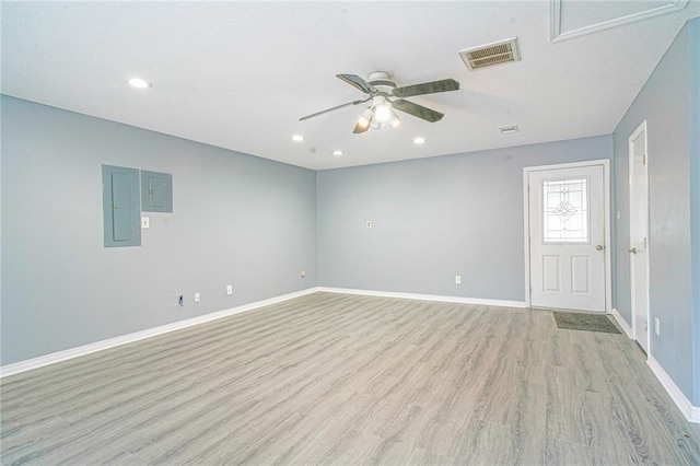 spare room featuring electric panel, ceiling fan, and light hardwood / wood-style floors