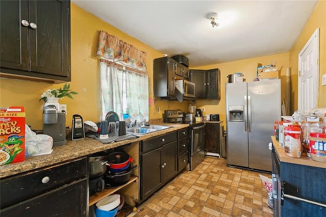 kitchen with dark brown cabinets, sink, light stone countertops, and stainless steel appliances