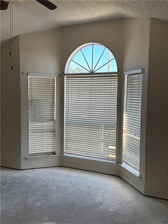 unfurnished room with ceiling fan, a textured ceiling, and concrete floors