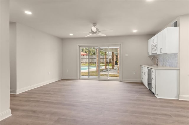 kitchen with white cabinetry, sink, stainless steel dishwasher, and light wood-type flooring