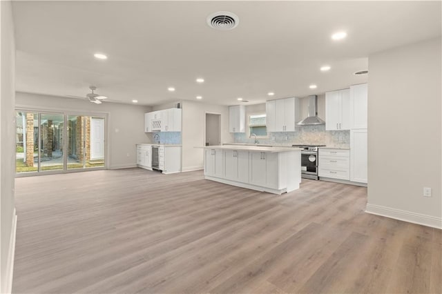 kitchen featuring white cabinetry, wall chimney range hood, stainless steel range, and light wood-type flooring