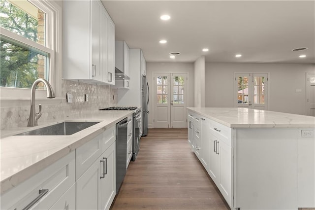 kitchen with light stone countertops, a center island, sink, and white cabinets