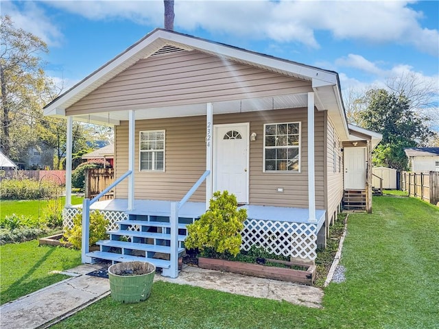 bungalow-style home featuring covered porch and a front yard