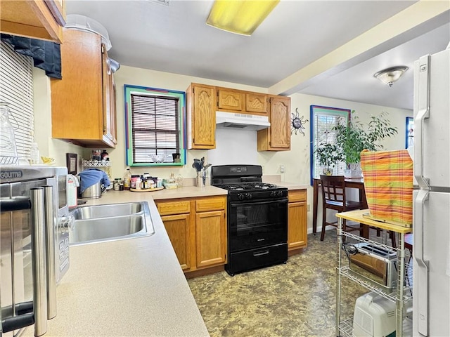 kitchen with white fridge, black range with gas stovetop, and sink