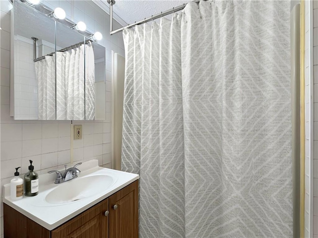 bathroom with curtained shower, a textured ceiling, decorative backsplash, vanity, and tile walls