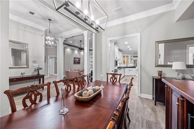 dining area with ornate columns, a chandelier, light hardwood / wood-style floors, and ornamental molding