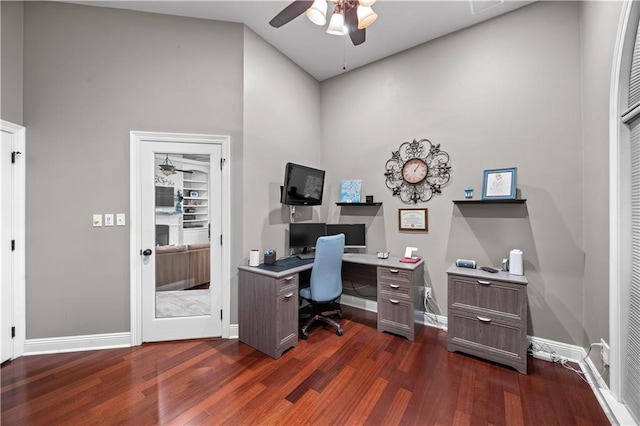 home office with a high ceiling, dark hardwood / wood-style flooring, and ceiling fan