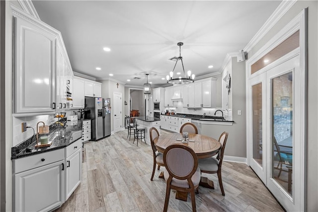 dining area with crown molding, french doors, a notable chandelier, and light wood-type flooring