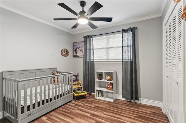 bedroom with ceiling fan, a closet, crown molding, and a crib