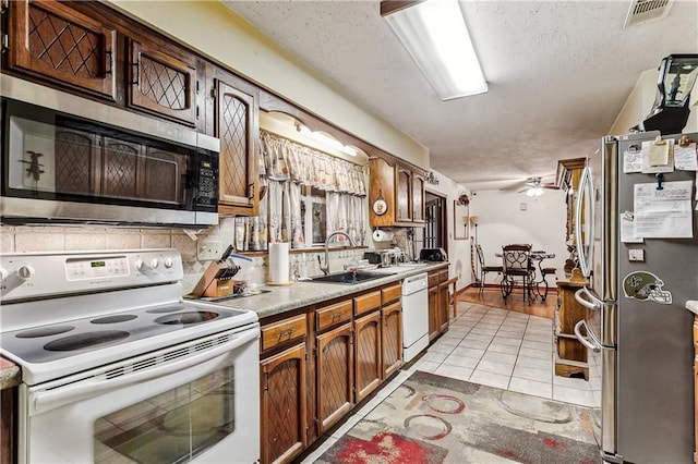 kitchen with sink, ceiling fan, a textured ceiling, light tile patterned flooring, and stainless steel appliances