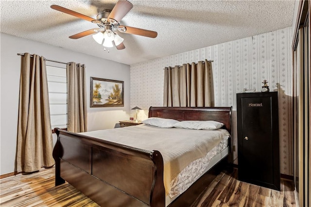 bedroom with ceiling fan, wood-type flooring, and a textured ceiling