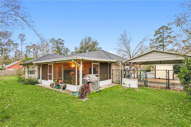 back of house featuring a lawn, a sunroom, and a carport