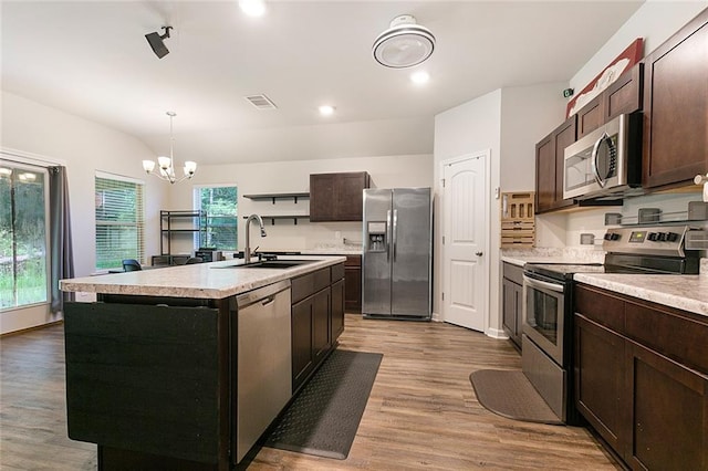 kitchen featuring sink, hanging light fixtures, stainless steel appliances, an inviting chandelier, and a center island with sink