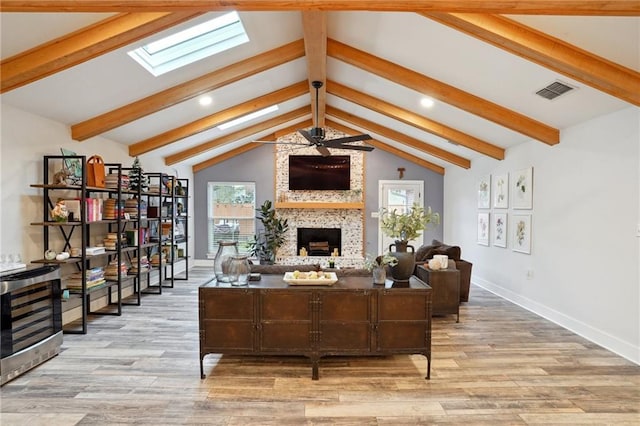 living room featuring a fireplace, light hardwood / wood-style flooring, and vaulted ceiling with skylight