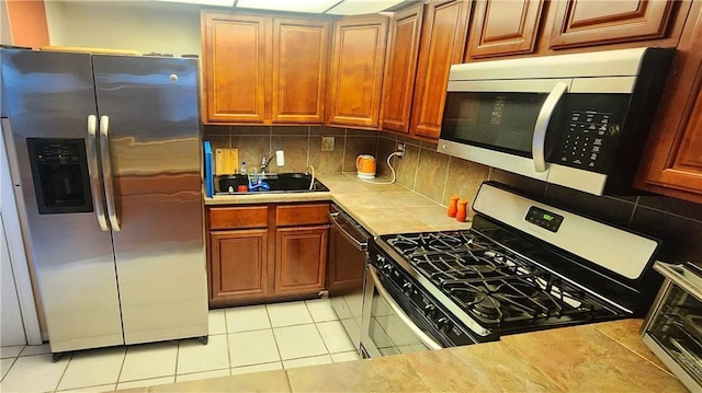 kitchen featuring tasteful backsplash, sink, light tile patterned floors, and stainless steel appliances